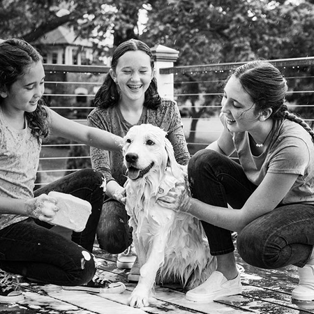 Young girls washing dog on deck