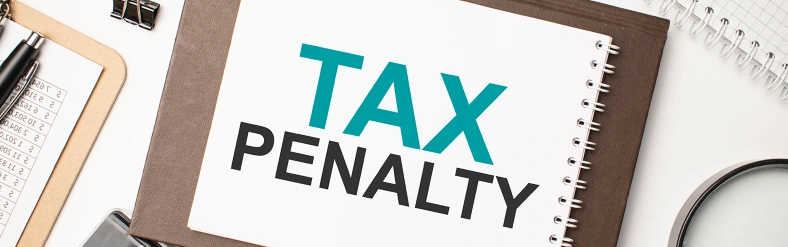Notebook labeled “tax penalty” on a desk with office supplies, representing IRS penalties and tax filing consequences.