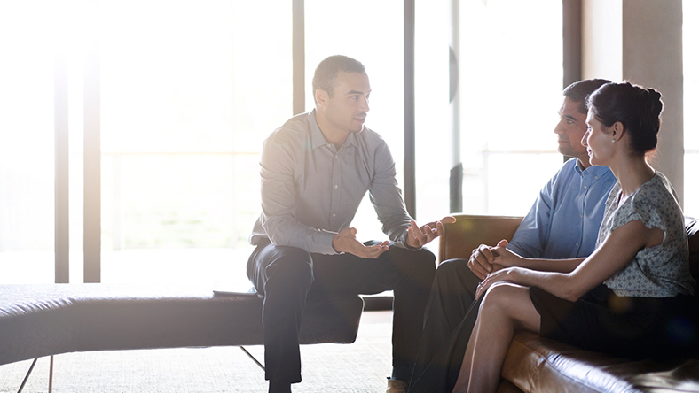 A couple sitting down listening to a man advise them