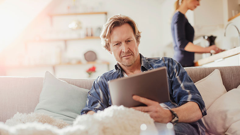 Man sitting on a couch looking at his tablet