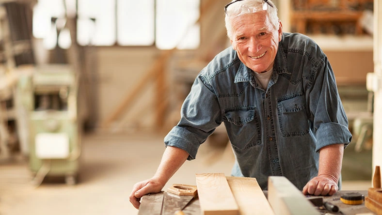 Older adult working on a woodworking project in a workshop, representing earning extra income during retirement.