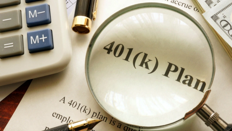 Magnifying glass over 401(k) plan document with calculator and cash, representing retirement savings and contribution limits