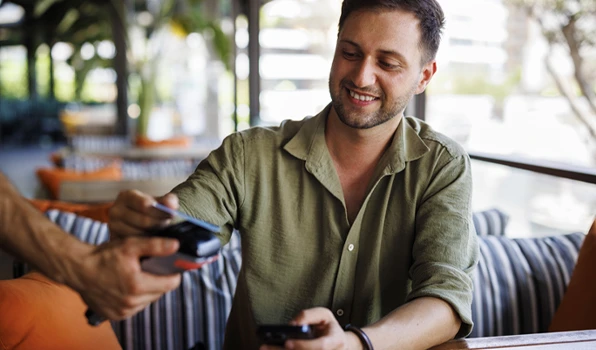 Customer using a debit card for a contactless payment at a restaurant, highlighting fast, secure access to checking account funds for everyday purchases.
