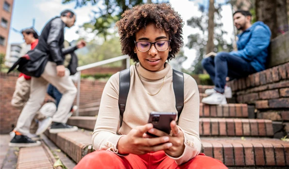 Person managing finances on a smartphone in an outdoor setting, highlighting easy access to digital banking services, account balances, transfers, and mobile banking tools.