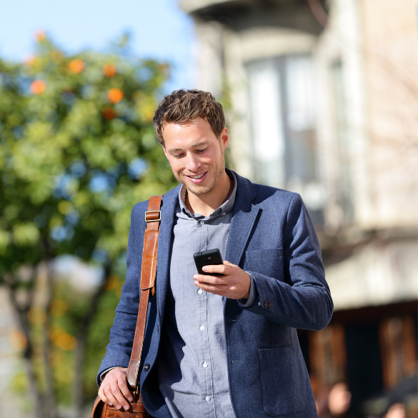 Smiling businessman using mobile phone outside.