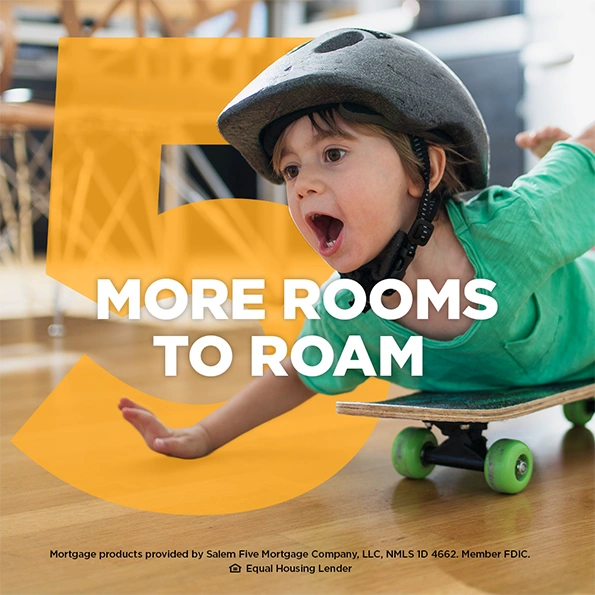 Young child wearing a helmet riding a skateboard indoors with the text “More Rooms to Roam”