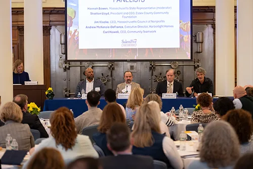 Panel discussion at a Salem Five nonprofit event with moderator at podium, four panelists seated at a table, and audience in a conference room.