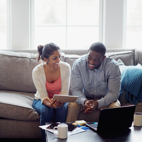 Happy couple sitting on couch with laptop,