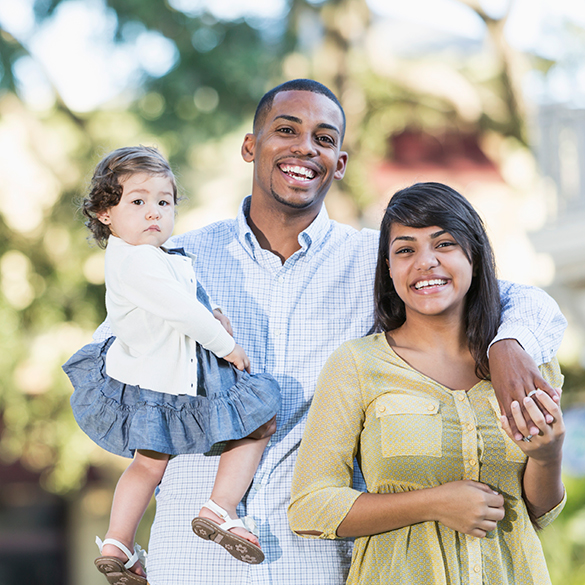 Young couple standing outside holding baby girl.