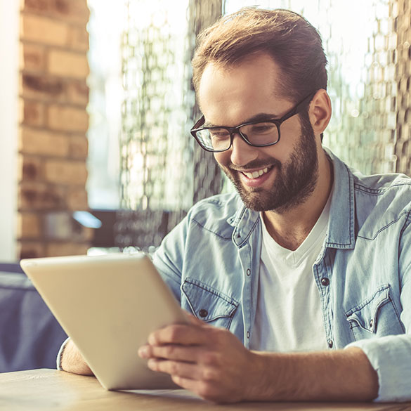 Young man smiling while using tablet device.