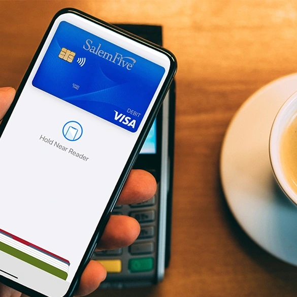 iPhone using Apple Pay with Salem Five Visa debit card at a payment terminal.